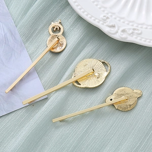 Tres pinzas de pelo de metal dorado con formas celestiales sobre tela verde suave
