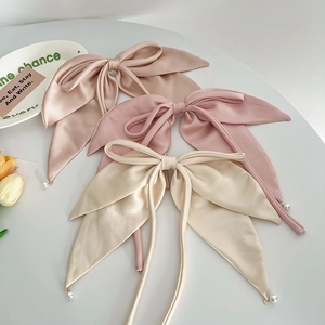 Three satin bow hair clips in pink and beige with elegant pearl pendants on ribbons