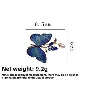 Detail of embroidered blue butterfly brooch with gold leaves and white drop pearl