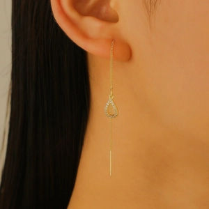 Close-up of golden drop tassel earrings with sparkling zircons worn by a model