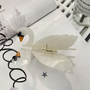 Detail of white swan hair claw clip made of acetate resin with metal spring on a magazine