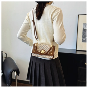 Detail van vintage crossbodytas met golfpatroon en gouden bloemvormig slot