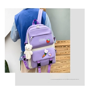 Detail of purple canvas backpack with cute pins and plush bear pendant accessory