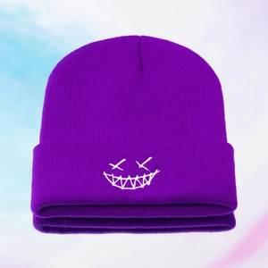 Close-up of purple knit beanie featuring white embroidered ghost face and jagged smile