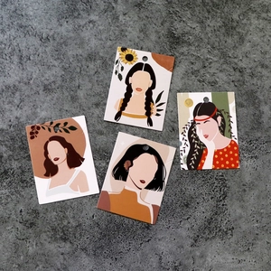 Detailed view of artistic female illustration jewelry display cards on stone floor