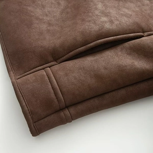 Detailed close-up of brown suede jacket showing stitching and pocket texture