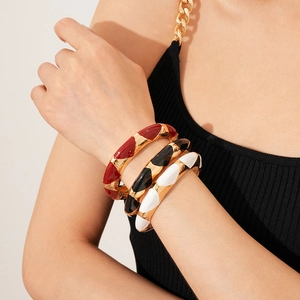 Close-up of French vintage open bangles in red, black, and white enamel with gold edges