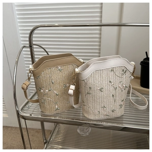 Détail de seaux en paille tissée avec broderies florales et lanières en cuir PU
