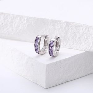 Détail de créoles en argent 925 avec des pierres de zircone violettes de coupe carrée