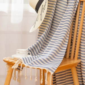 Striped cotton Turkish beach towel with fringe hanging on a wooden chair