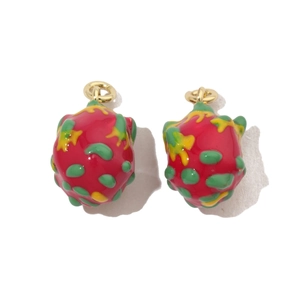 Macro shot of red dragon fruit enamel pendant with green scales and gold hanging ring