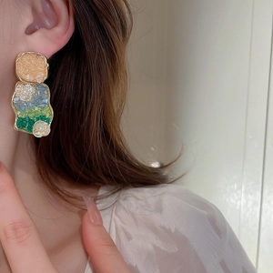 Exaggerated floral earrings with crystals and pearls worn by a model in profile