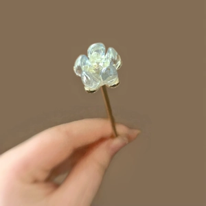 Detailed close-up of a blue lotus hair pin featuring translucent petals and metal stem