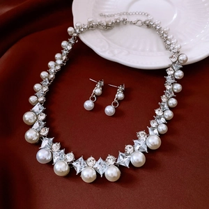 Detail von luxuriösem Perlen- und Kristallschmuckset auf edlem dunkelrotem Seidengrund