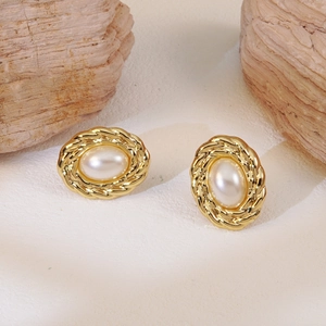 Detailed macro shot of vintage gold oval earrings with pearl in twisted metal frame
