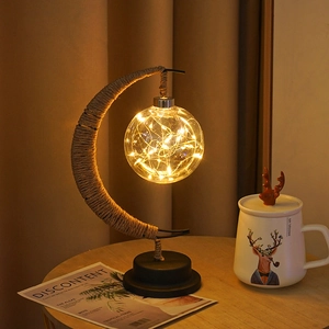Detail of moon-shaped LED lamp with twine metal frame and warm glowing glass bulb
