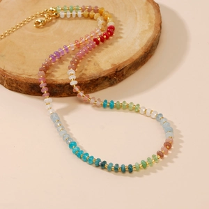 Colorful beaded gemstone necklace with gold spacers on a wooden base for beach fashion
