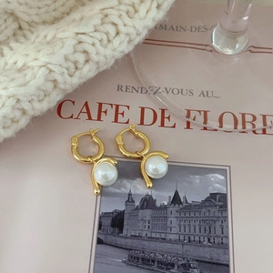 Detail of gold circular hoop earrings with elegant white pearls on a textured background