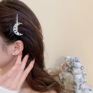 Detail of moon hair clip with rhinestones and pearl earring on a model