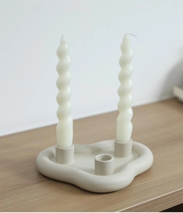 Détail du bougeoir en céramique mat en forme de nuage sur une table en bois