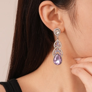 Detailed close-up of luxury purple teardrop crystal drop earrings worn by a female model