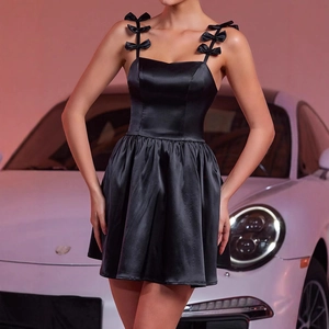 Détail d'une mini robe en satin noir avec bretelles à nœuds et finition brillante