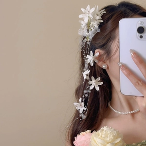 Detail of floral lace hair clip with pearls and long tassels for a beach vacation style