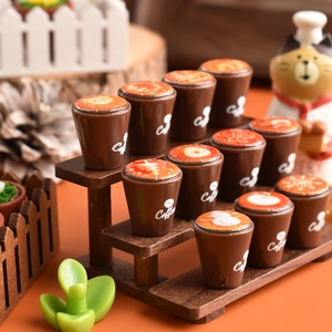 Miniature resin coffee cups with snowflake latte art displayed on a tiered wooden rack