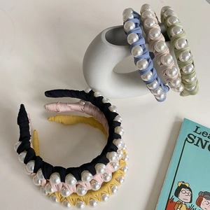Detail of colorful fabric headbands with large pearls arranged on a white table