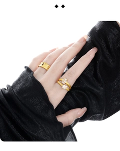 Detailansicht eines goldfarbenen Rings mit Zirkonia, getragen mit schwarzem Faltenärmel