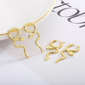Detailed macro of gold snake-shaped earrings featuring fine textured scales and metallic luster