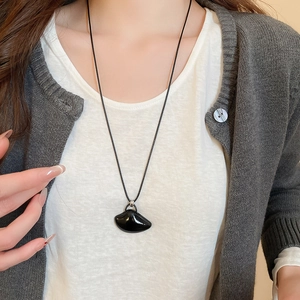 Minimalist black crescent pendant on cord shown on model for professional styling