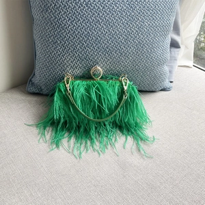 Detail view of emerald green ostrich feathers and gold metal handle with crystal ring