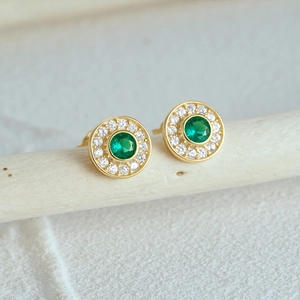 Macro shot of S925 silver round gold studs with emerald gemstone and diamond halo