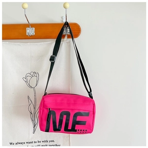 Détail d'un sac bandoulière rose en nylon avec sangle réglable et imprimé de lettres
