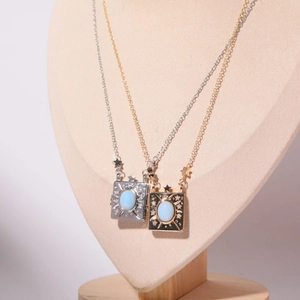Detail of gold and silver locket necklaces with opal stones on jewelry display stands