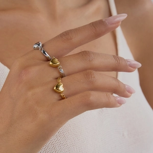 Minimalistische wendbare Herzringe aus 18K Gold und Edelstahl am Finger eines Models