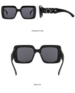 Detail of square sunglasses featuring wide hollow chain temples and Greek fret motifs