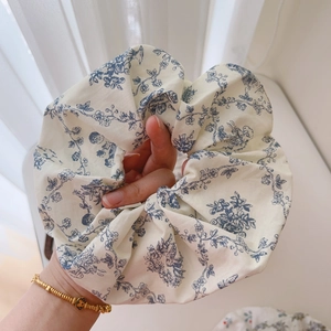 Detailed view of oversized off-white scrunchie with blue floral print and cotton texture