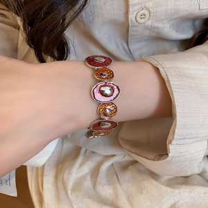 Detail of vintage red and orange enamel metal bracelet worn on a female wrist