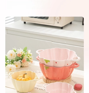 Close-up of pumpkin shaped ceramic bowls with handles in pink, orange and beige colors