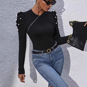 Detail of elegant black top with puffed sleeves, pearl embellishments, and side zipper