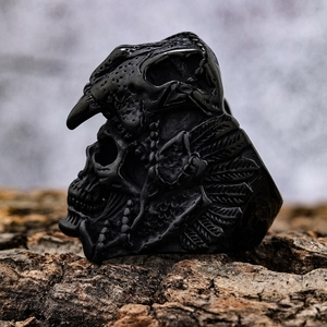 Gothic skull ring with bird helmet in black oxidized metal on natural bark background