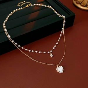 Détail du collier double couche doré avec pendentif cœur blanc, perle et zircon brillant