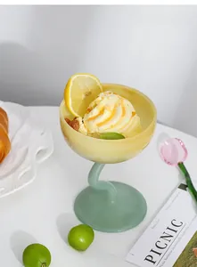 Detail of elegant yellow glass dessert bowl with a wavy green stem for ice cream