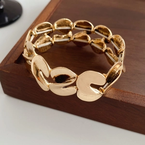 Detail view of gold S-shaped metallic links on elastic stretch fashion bracelet