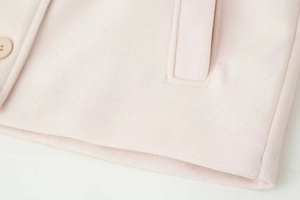 Detail of pink wool jacket showing double-breasted button closure and pocket stitching