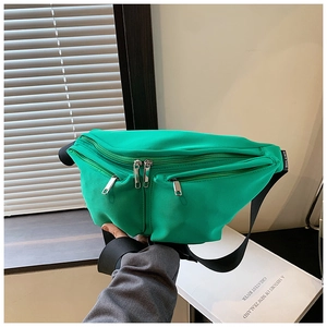 Detailed view of neon green nylon crossbody bag with dual silver zippers and multi-pockets