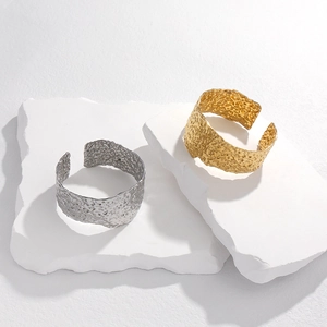 Macro detail of wide open cuff bracelets featuring gold and silver hammered metal textures