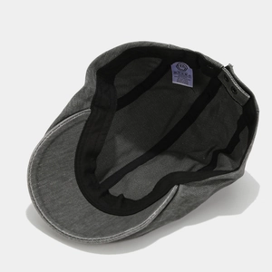 Detail view of cotton newsboy cap with neat stitching and adjustable side buckle strap